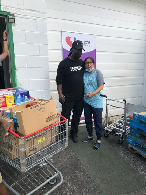 Two people with a cart of boxed groceries ready for families